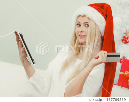 Woman in Santa hat holding tablet and credit card 137709839