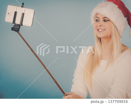 Girl in santa hat taking picture of herself using selfie stick 137709858