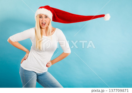 Surprised girl wearing blowing santa claus hat Surprised girl wearing blowing santa claus hat 137709871