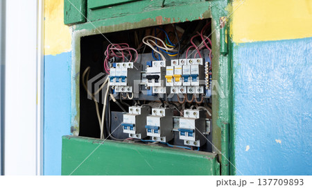 Built-in distribution board with fuses or circuit breakers and connected wires in an old industrial building. 137709893
