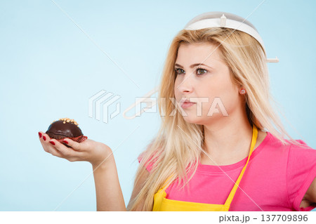 Woman holding cupcake wearing colander on head Woman holding cupcake wearing colander on head 137709896