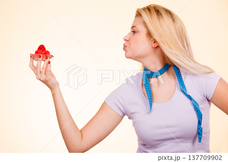 Woman with measuring tape holding sweet cupcake 137709902