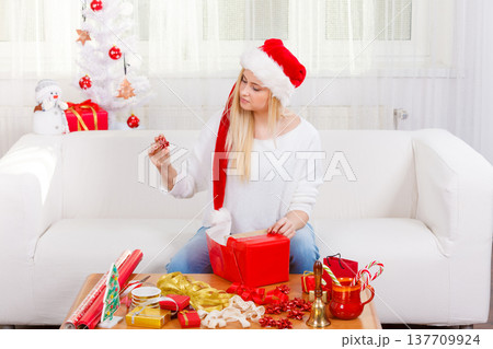 Woman in Santa hat packing christmas gifts Woman in Santa hat packing christmas gifts 137709924