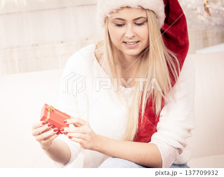 Woman in Santa hat opening christmas presents 137709932