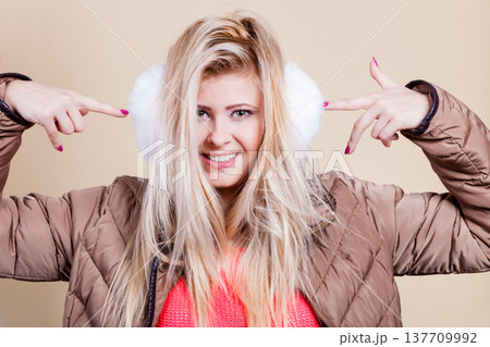 Woman wearing winter furry earmuffs pointing at them 137709992