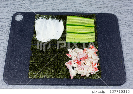 Creamy crab stick and mayonnaise mixture added to third quarter of nori sheet. Next layer in building lazy sushi sandwich after cucumber. Step by step homemade Japanese recipe tutorial 137710316