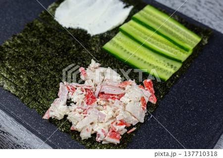 Nori sheet quarters topped with cream cheese, cucumber slices, and crab mixture. Colorful Japanese inspired appetizer bites perfect for parties. Elegant finger food presentation on dark surface Nori sheet quarters topped with cream cheese, cucumber slices, and crab mixture. Colorful Japanese inspired appetizer bites perfect for parties. Elegant finger food presentation on dark surface 137710318