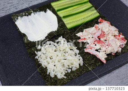 Nori sheet fully loaded with cream cheese, cucumber, crab, and rice. Perfect make-ahead filling for portable Japanese-style sandwich. Ideal for bento boxes, picnics, and healthy office lunches 137710323