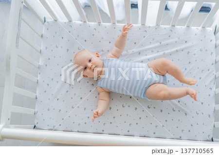 Baby lying peacefully in a cozy crib at home, feeling safe and calm in a warm nursery atmosphere. Simple everyday moment of care and comfort. Infant sleep, early childhood and gentle parenting concept Baby lying peacefully in a cozy crib at home, feeling safe and calm in a warm nursery atmosphere. Simple everyday moment of care and comfort. Infant sleep, early childhood and gentle parenting concept 137710565