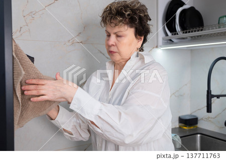 Senior woman cleaning kitchen countertop at home Senior woman cleaning kitchen countertop at home 137711763