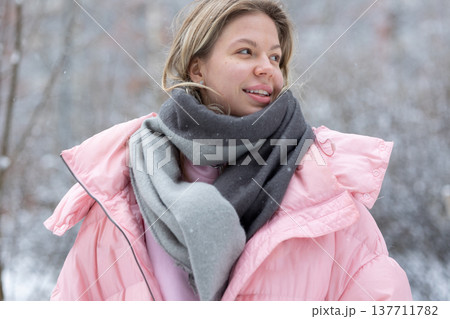 Smiling young blonde woman in pink winter jacket outdoors Smiling young blonde woman in pink winter jacket outdoors 137711782