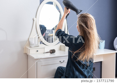 Woman drying hair at vanity mirror Woman drying hair at vanity mirror 137711790