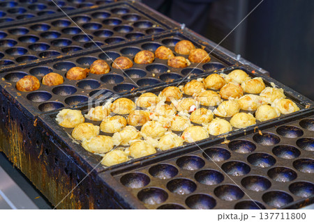 Osaka, Japan - Sep 21 2024, A close-up view of takoyaki cooking in a frying pan, a national Japanese dish in the form of fried balls with octopus, Osaka, Japan Osaka, Japan - Sep 21 2024, A close-up view of takoyaki cooking in a frying pan, a national Japanese dish in the form of fried balls with octopus, Osaka, Japan 137711800