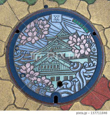 Osaka, Japan - Sep 21 2024, Close-up view of a manhole cover with a colourful image of Osaka Castle , Osaka, Japan 137711846