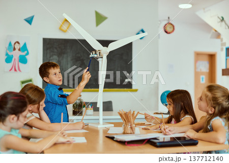 Children exploring a model wind turbine in a classroom STEM activity about renewable energy 137712140