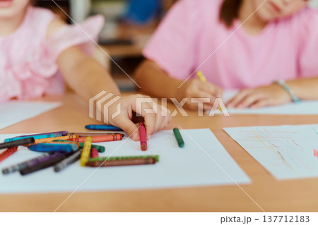 Children drawing with crayons at a classroom table, creative kids making colorful artwork together Children drawing with crayons at a classroom table, creative kids making colorful artwork together 137712183