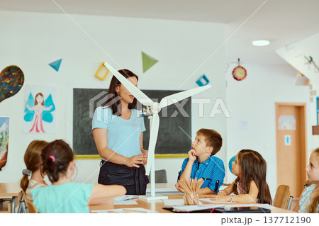 Teacher demonstrates a small wind turbine to engaged elementary students during a hands-on STEM classroom lesson 137712190