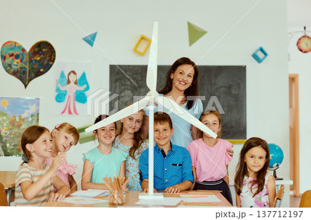 Teacher and elementary students with a wind turbine model in classroom STEM project, smiling and engaged 137712197