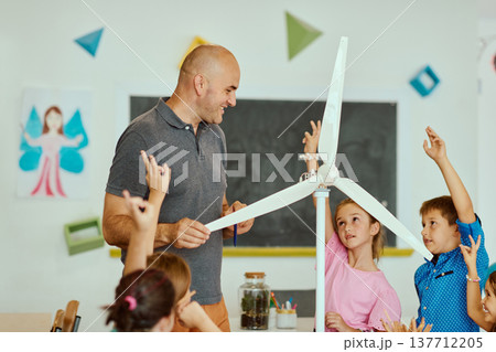 Teacher and elementary students explore a model wind turbine during a hands-on STEM lesson in the classroom Teacher and elementary students explore a model wind turbine during a hands-on STEM lesson in the classroom 137712205