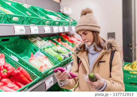 Woman counting calories on smartphone during grocery shopping Woman counting calories on smartphone during grocery shopping 137712913
