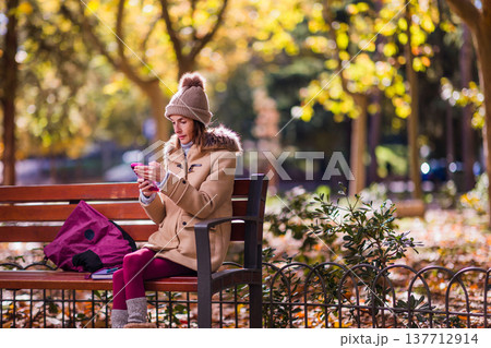 woman with eating disorders sitting on park bench using smartphone 137712914