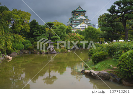 Osaka, Japan - Sep 22 2024, panoramic view of Osaka Castle on a rainy day, in the foreground a park with a pond with a heron in it, cloudy sky, daytime, Osaka, Japan Osaka, Japan - Sep 22 2024, panoramic view of Osaka Castle on a rainy day, in the foreground a park with a pond with a heron in it, cloudy sky, daytime, Osaka, Japan 137713261