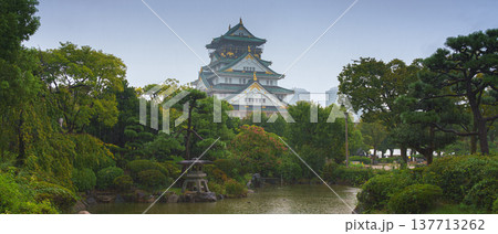 Osaka, Japan - Sep 22 2024, panoramic view of Osaka Castle on a rainy day, in the foreground a park with a pond with a heron in it, cloudy sky, daytime, Osaka, Japan 137713262