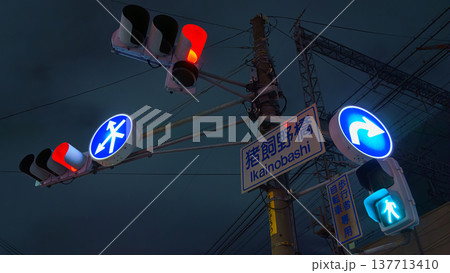 Osaka, Japan - Sep 22 2024, panoramic view from below of road signs with a man and an arrow and road and pedestrian traffic lights on a pillar, in the background dark night sky, Osaka, Japan Osaka, Japan - Sep 22 2024, panoramic view from below of road signs with a man and an arrow and road and pedestrian traffic lights on a pillar, in the background dark night sky, Osaka, Japan 137713410