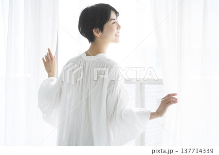 日常生活を送る若い女性 カーテンを開けて外を見る  137714339