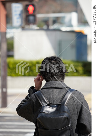 冬の昼の名古屋の繁華街の交差点で信号待ちの若い男性サラリーマンの姿 冬の昼の名古屋の繁華街の交差点で信号待ちの若い男性サラリーマンの姿 137715396