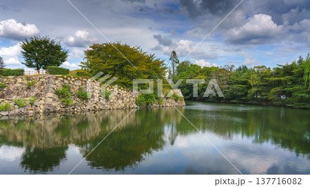 Himeji, Japan - Sep 24 2024, panoramic view of pond with mirrored water, bridge in front of fortress wall of Himeji Castle, White Heron Castle, at daytime, without people, Himeji, Japan 137716082