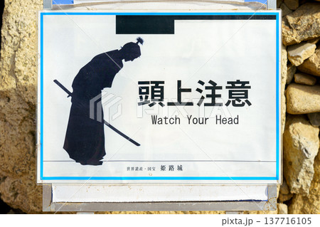Himeji, Japan - Sep 24 2024, A close-up view of a warning sign depicting a black silhouette of a samurai and the inscription Watch your head, at Himeji Castle, White Heron Castle, Himeji, Japan Himeji, Japan - Sep 24 2024, A close-up view of a warning sign depicting a black silhouette of a samurai and the inscription Watch your head, at Himeji Castle, White Heron Castle, Himeji, Japan 137716105