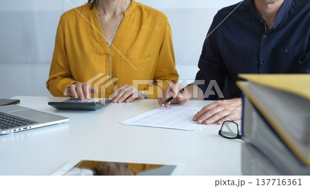 Professional team analyzing contract details, reviewing financial documents, calculating costs at collaborative workplace with laptops and paperwork. Audit and taxes in business Professional team analyzing contract details, reviewing financial documents, calculating costs at collaborative workplace with laptops and paperwork. Audit and taxes in business 137716361