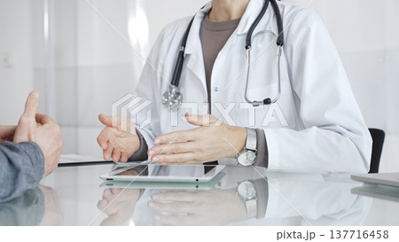 Doctor consulting patient, discussing diagnosis, using digital tablet in modern medical clinic. Medicine and health care Doctor consulting patient, discussing diagnosis, using digital tablet in modern medical clinic. Medicine and health care 137716458
