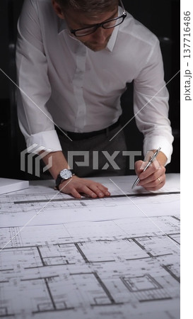 Architect drawing floor plan blueprint with ruler and pen, designing new building construction project. Concept of architecture and business in low key lighting Architect drawing floor plan blueprint with ruler and pen, designing new building construction project. Concept of architecture and business in low key lighting 137716486