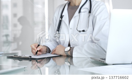 Doctor writing prescription or medical record, providing patient care and healthcare services in clinic. Medicine and health care Doctor writing prescription or medical record, providing patient care and healthcare services in clinic. Medicine and health care 137716602