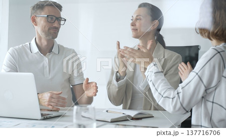 Business people applauding after achieving a goal during a productive meeting in a modern office environment, celebrating success and teamwork 137716706