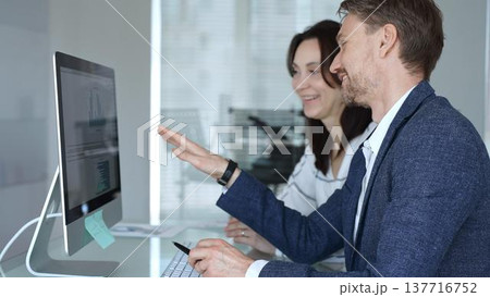 Business colleagues collaborating on data analysis, watching financial graphs and charts on computer monitor. Businesspeople concept Business colleagues collaborating on data analysis, watching financial graphs and charts on computer monitor. Businesspeople concept 137716752