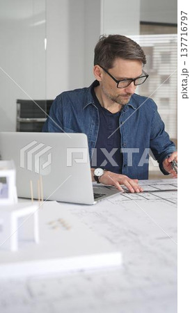 Architect man designing new building structure, carefully developing a modern architectural model in office, focusing on creating innovative housing plans and contemporary development concepts Architect man designing new building structure, carefully developing a modern architectural model in office, focusing on creating innovative housing plans and contemporary development concepts 137716797