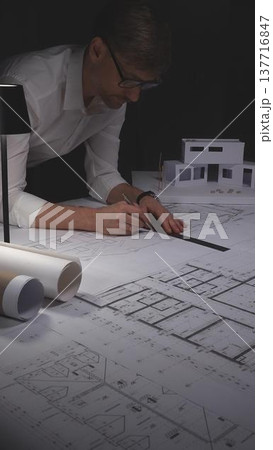 Architect working on blueprint with compass, developing engineering plans and creative building design. Concept of architecture and business in low key lighting 137716847