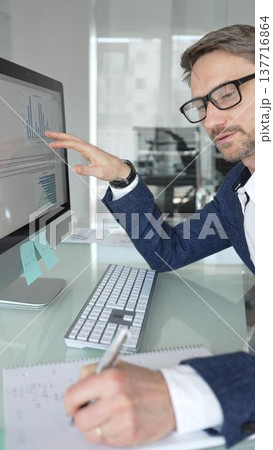 Professional businessman in a blue jacket working on desktop computer in modern office, focusing on his work and business tasks. Business people concept Professional businessman in a blue jacket working on desktop computer in modern office, focusing on his work and business tasks. Business people concept 137716864