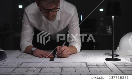 Architect working on blueprints late at night, focusing on construction plans and project engineering design. Business and architect people concept Architect working on blueprints late at night, focusing on construction plans and project engineering design. Business and architect people concept 137716881