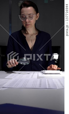 Financial audit and fraud detection using a magnifying glass, reviewing documents and calculating numbers. Audit and taxes in business Financial audit and fraud detection using a magnifying glass, reviewing documents and calculating numbers. Audit and taxes in business 137716944