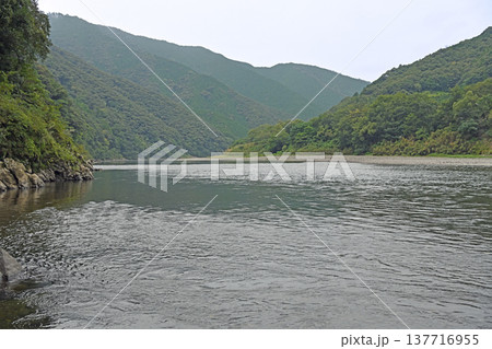 四万十川の広大な水面と岩間沈下橋周辺に連なる山々の風景 四万十川の広大な水面と岩間沈下橋周辺に連なる山々の風景 137716955