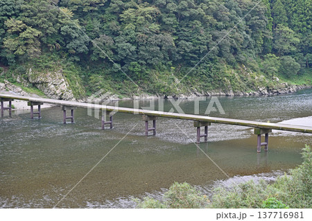 四万十川の岩間沈下橋と背後に迫る深い緑の山肌 四万十川の岩間沈下橋と背後に迫る深い緑の山肌 137716981