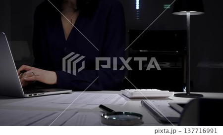Woman working on documents late at night under artificial light, managing finance, business, and accounting tasks. Audit and taxes in business 137716991