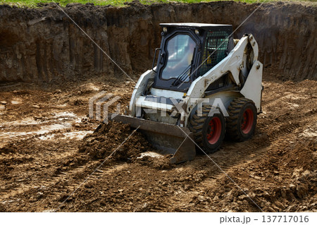 Heavy machinery moves dirt at a construction site with a clear focus on ground leveling and preparation for building Heavy machinery moves dirt at a construction site with a clear focus on ground leveling and preparation for building 137717016