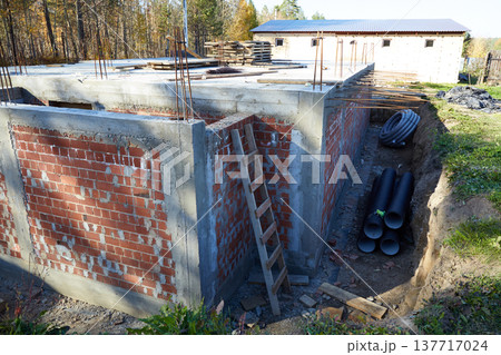 Construction of a building made of brick, concrete and steel reinforcement in a wooded area in autumn Construction of a building made of brick, concrete and steel reinforcement in a wooded area in autumn 137717024