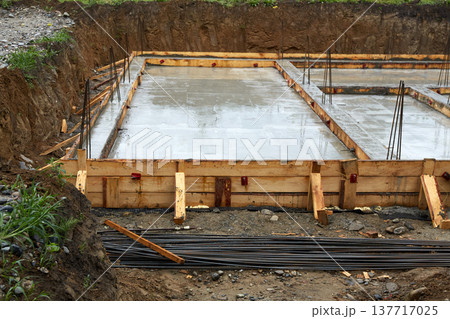 A concrete foundation is being poured on the construction site. Wooden formwork is used.  137717025