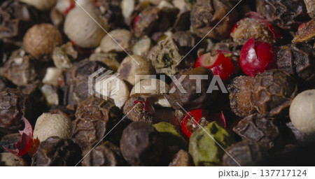 Various colorful spices and peppercorns arranged together in a bowl on a wooden table during daylight 137717124